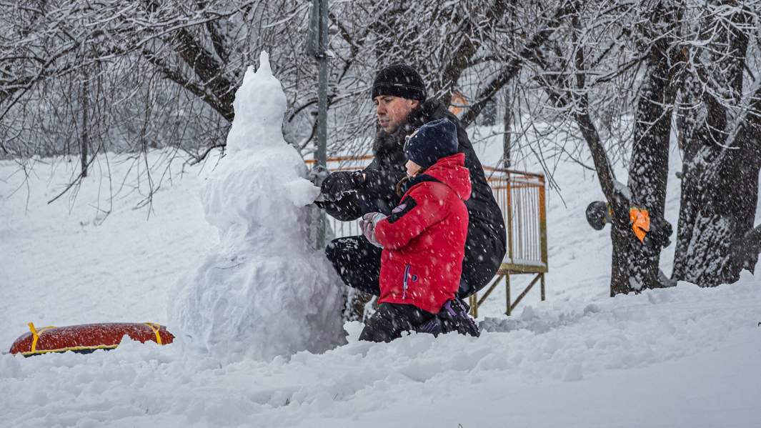 Мужчина с ребенком лепят снеговика