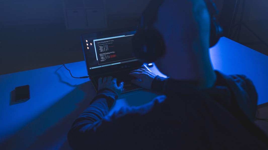 Хакер с ноутбуком в темной комнате