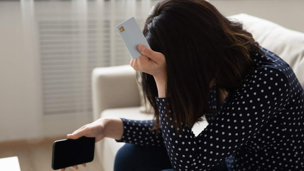 Расстроенная девушка с кредитной картой и телефоном