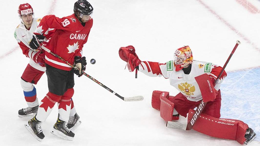 Игрок сборной России Артемий Князев, игрок сборной Канады Квинтон Байфилд и голкипер сборной России Ярослав Аскаров во время матча 1/2 финала молодежного чемпионата мира по хоккею между сборными России и Канады