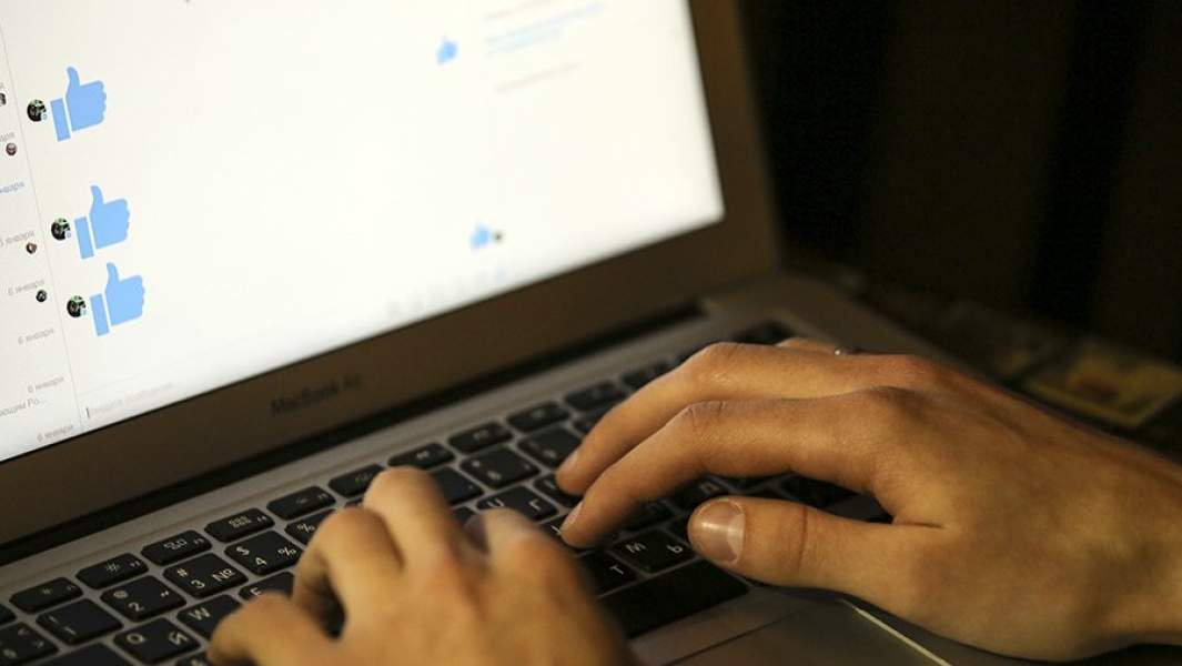 Человек за ноутбуком переписывается в соцсети