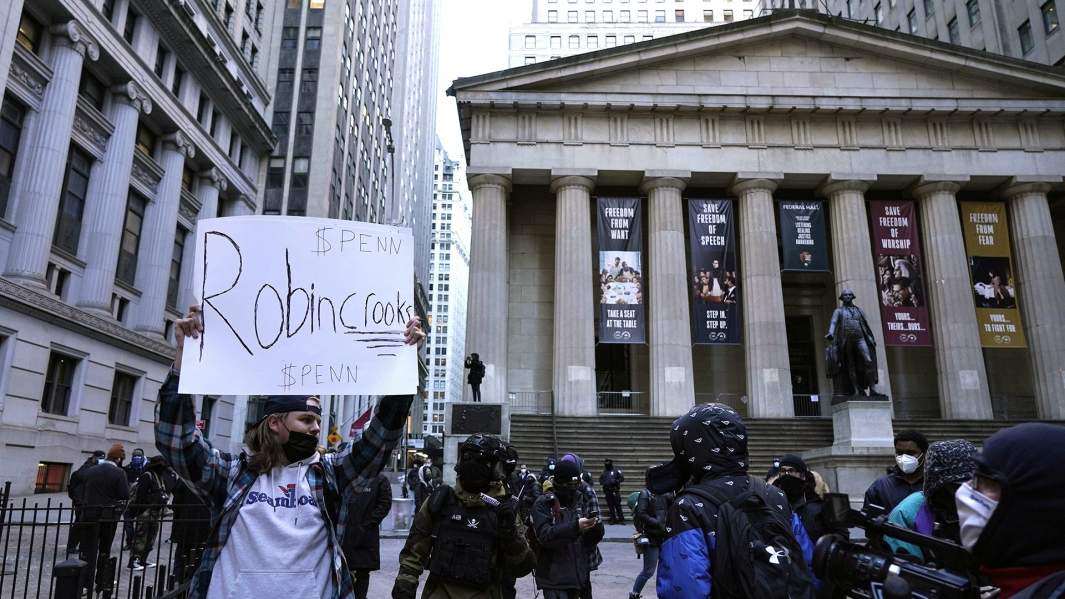 демонстрант с плакатом около нью-йоркской фондовой биржи