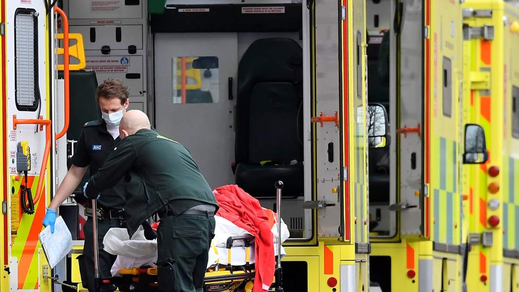 медицинские работники вывозят пациента из машины скорой помощи в Лондоне