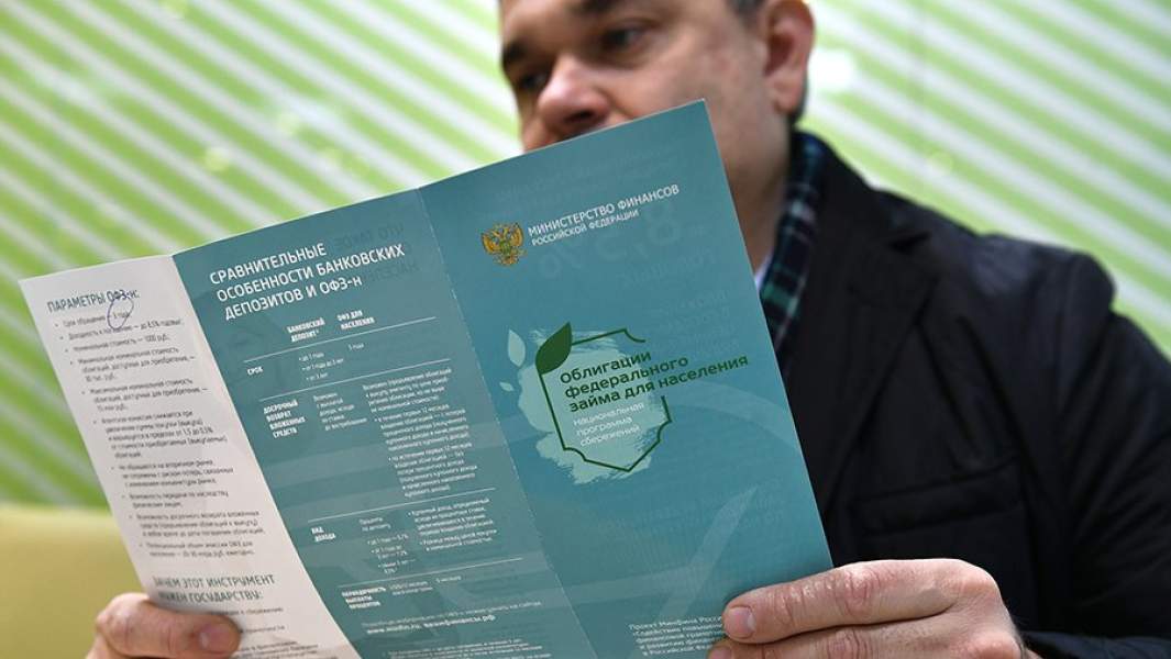 Мужчина в одном из отделений банка изучает буклет о приобретении облигаций федерального займа