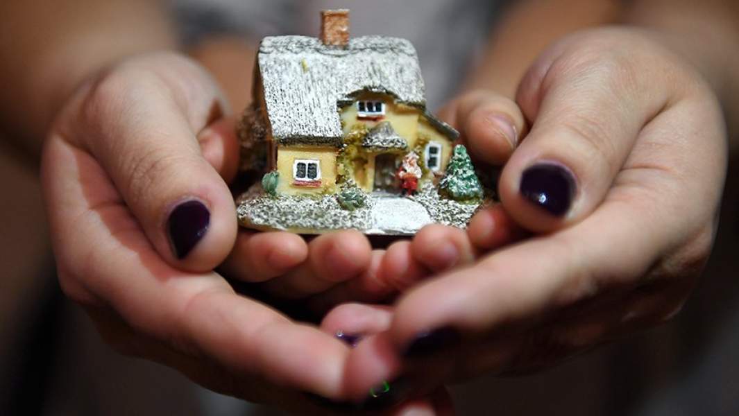 Женщина с ребенком держат макет дома