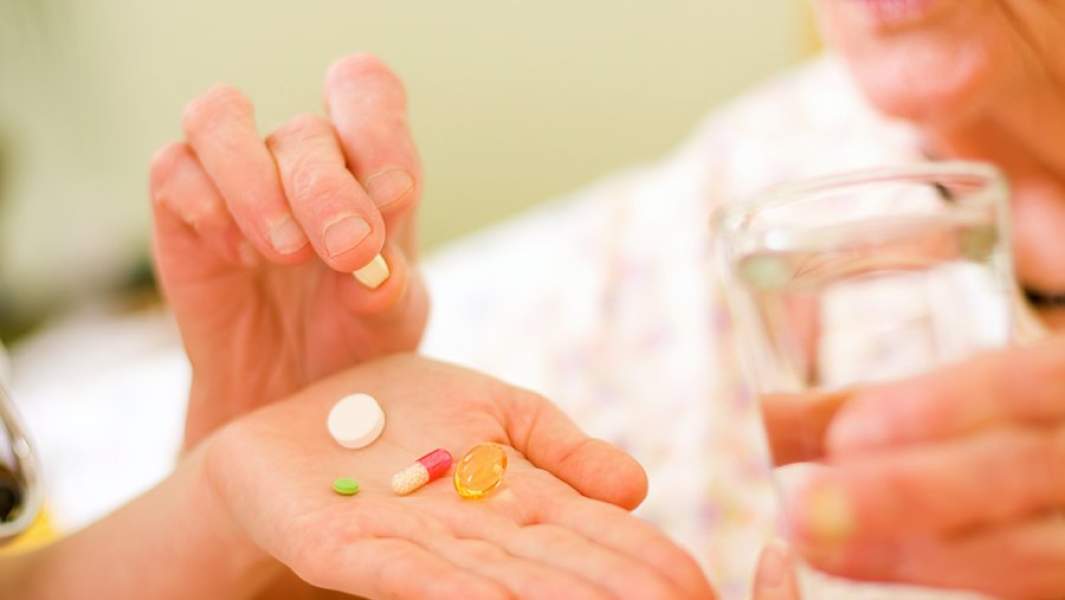 Пожилая женщина пьет таблетки