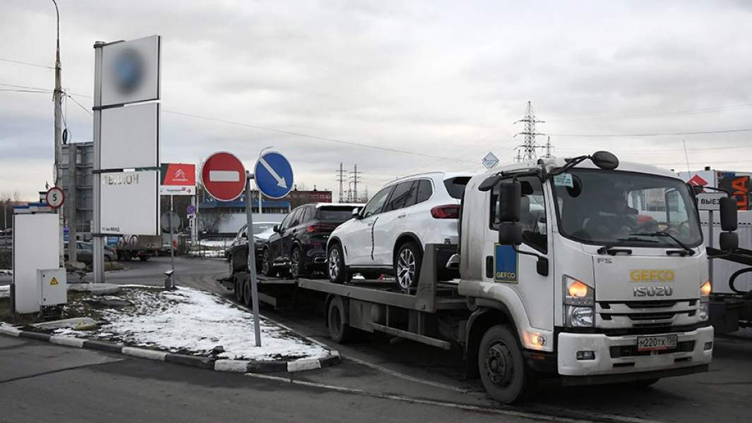 Автовоз с новыми автомобилями у автосалона