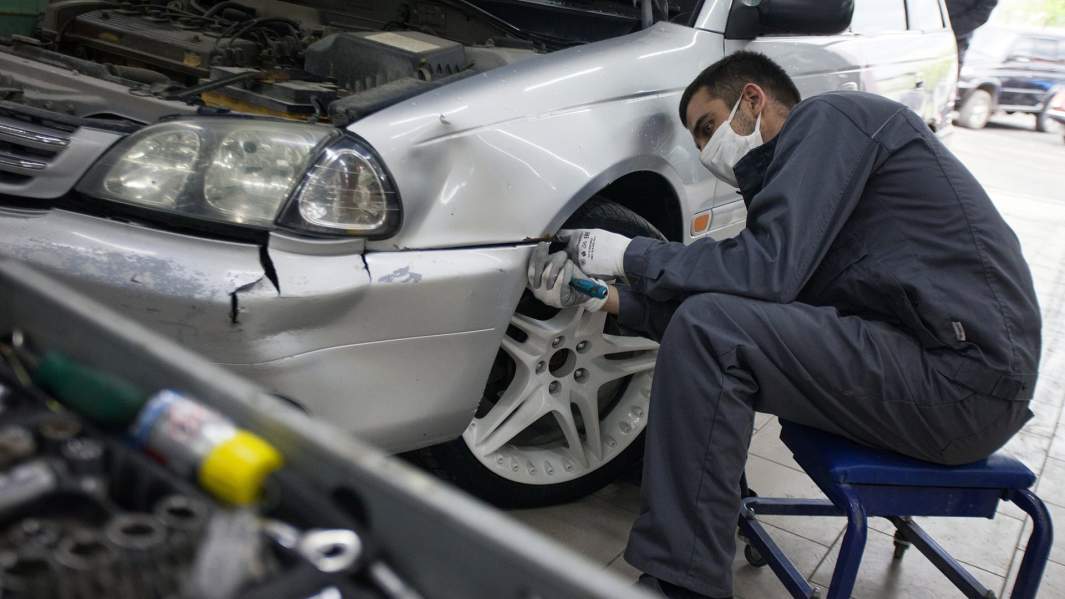 Сотрудник разбирает автомобиль перед дальнейшей покраской в центре кузовного ремонта