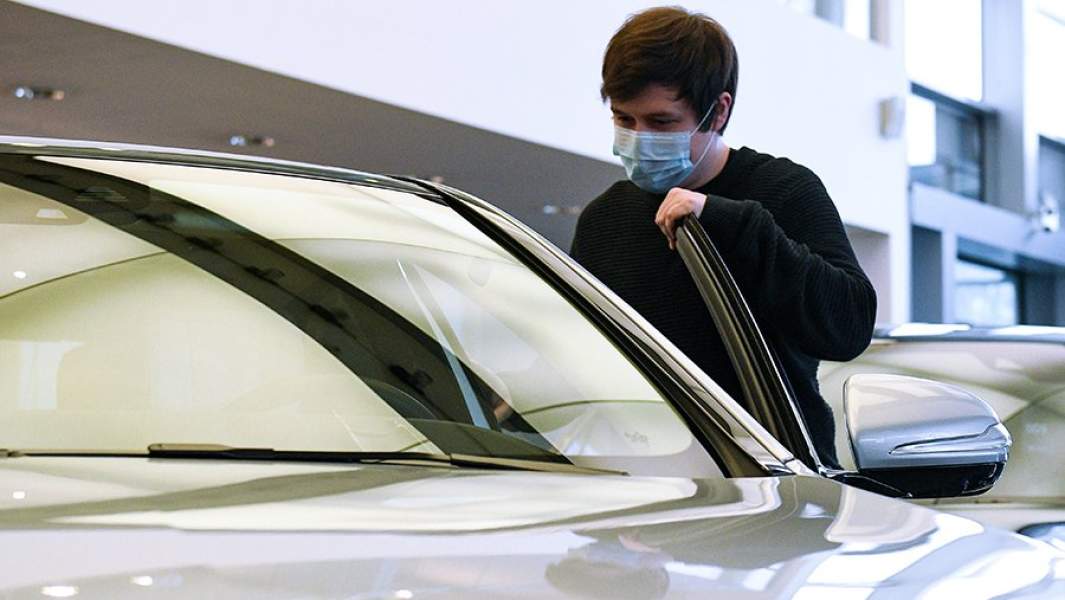 Менеджер демонстрирует покупателям автомобиль в автосалоне