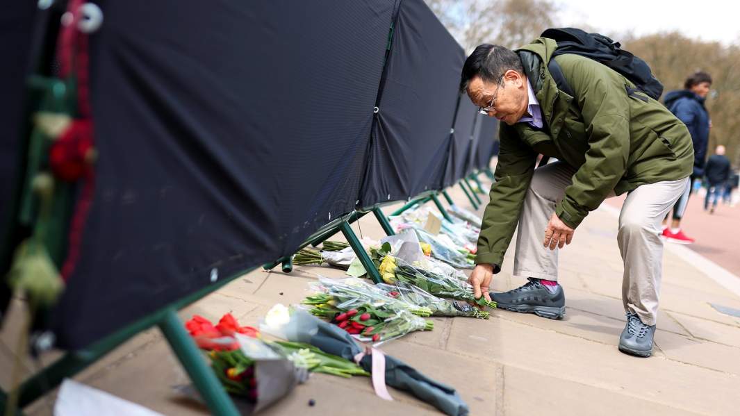 Мужчина возлагает цветы перед Букингемским дворцом после смерти принца Филиппа, герцога Эдинбургского и мужа королевы Елизаветы, Лондон, Великобритания