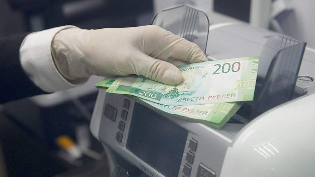Сотрудник у счетчика банкнот в офисе банка "Открытие"