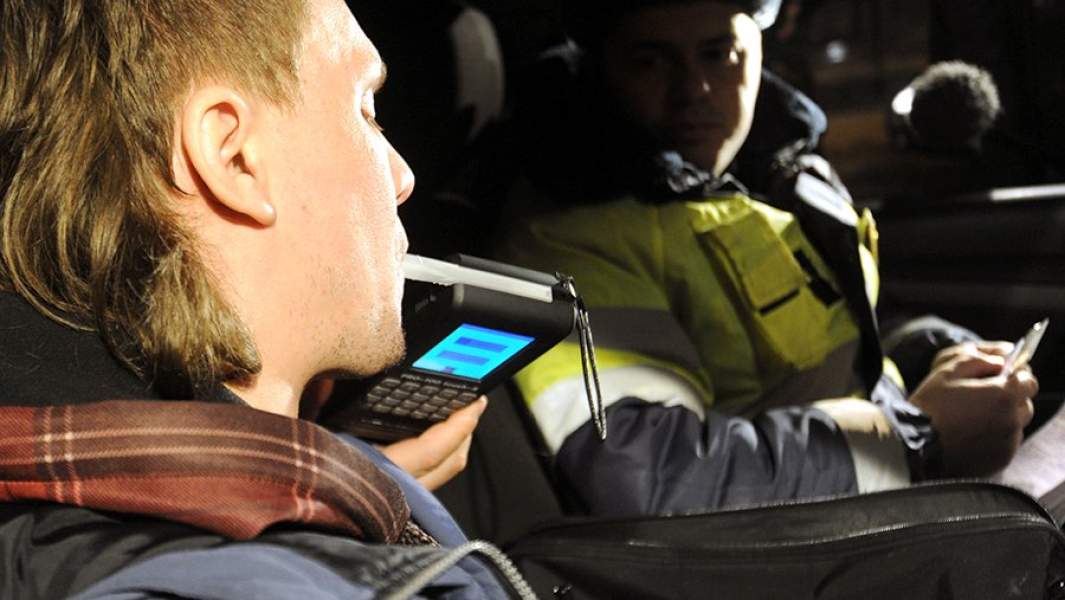 Сотрудник ГИБДД проверяет водителя алкотестером на содержание алкоголя в крови