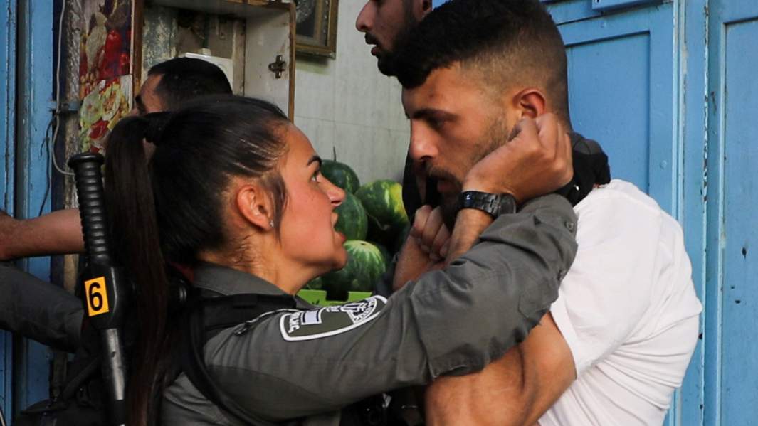 Сотрудник израильских сил безопасности  и протестующий 