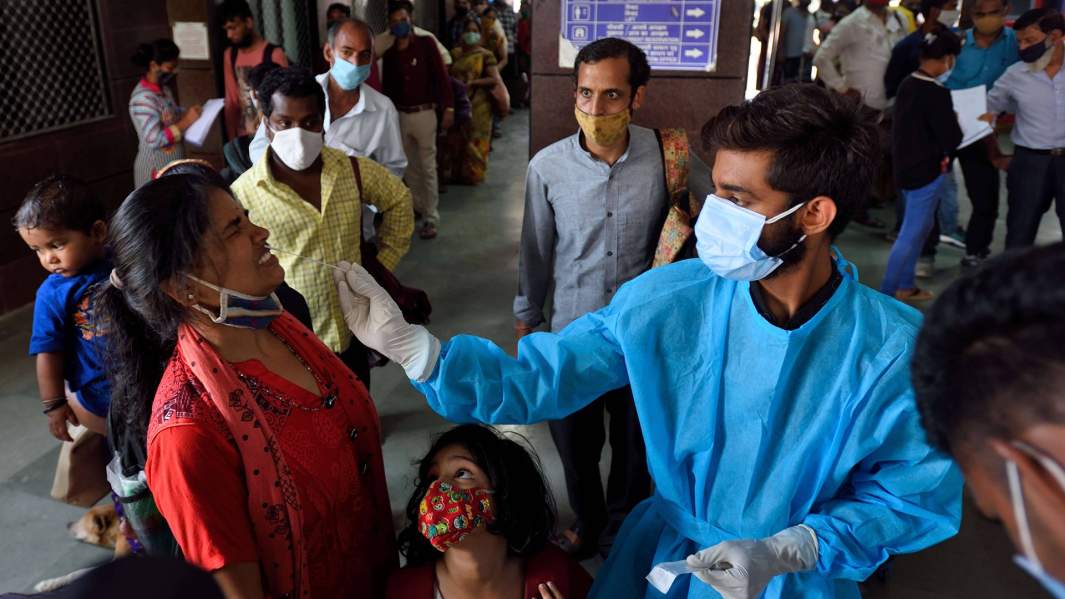 медицинский работник берет анализ на COVID-19 у пациентки в Индии