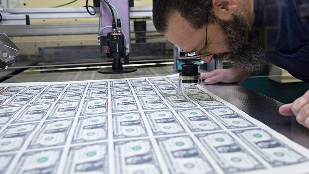 Мужчина проверяет отпечатанные доллары