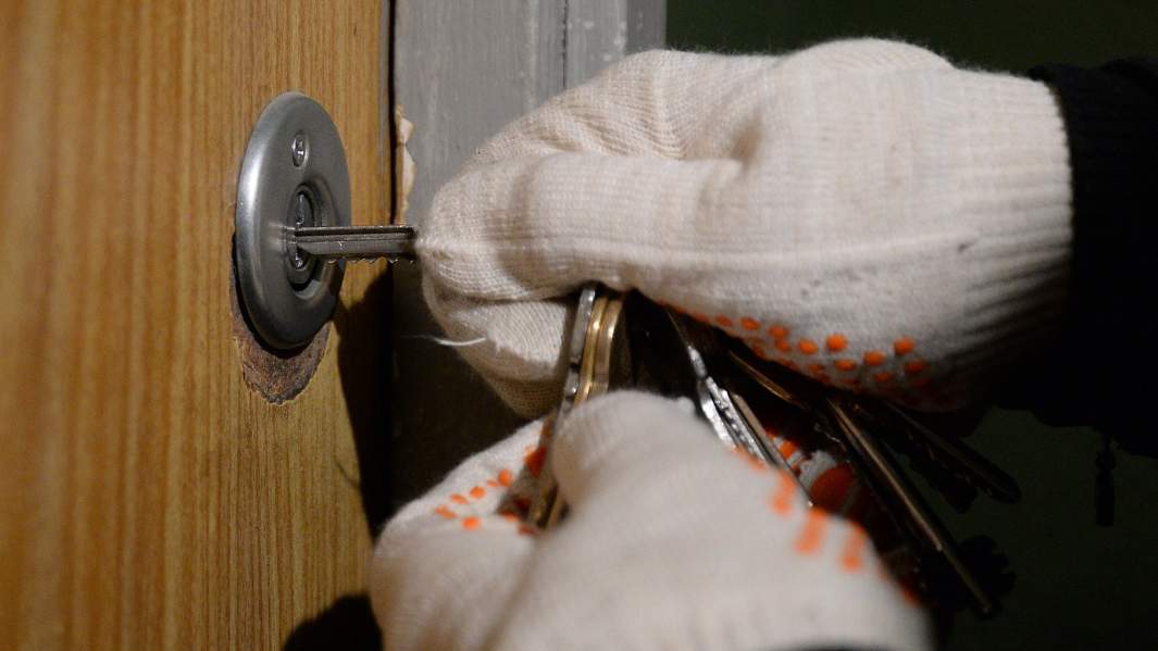 человек в перчатках пытается взломать замок