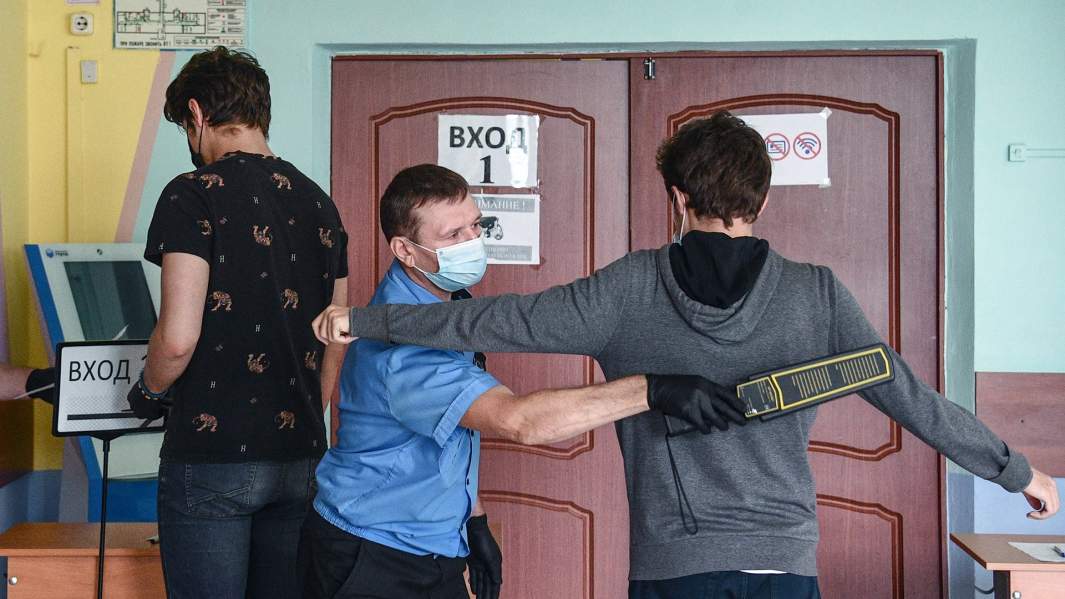 Сотрудник службы охраны осматривает учеников