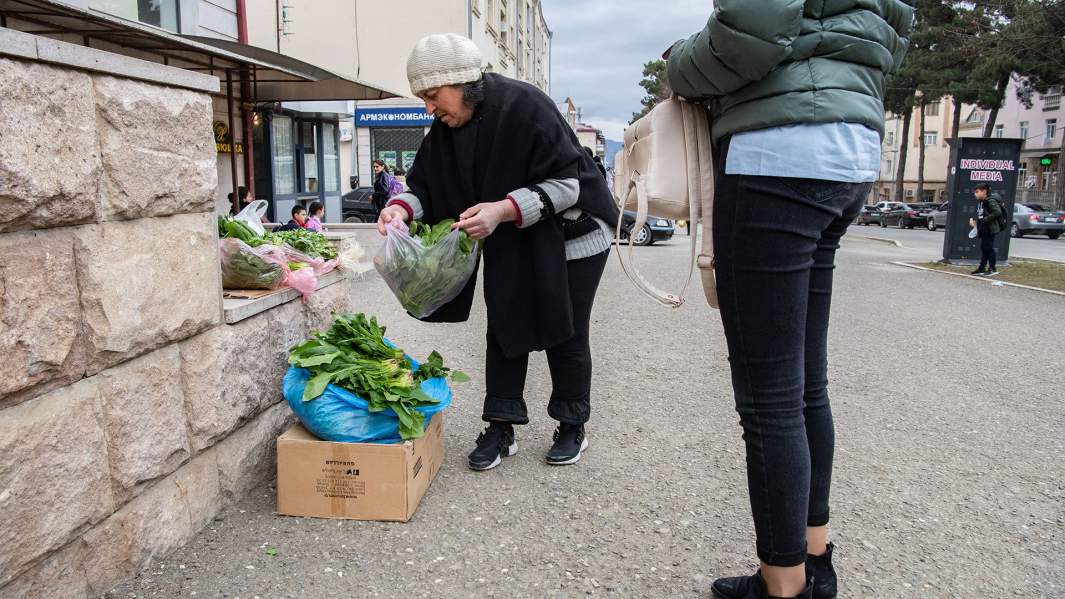 Женщина покупает зелень на улице Степанакерта