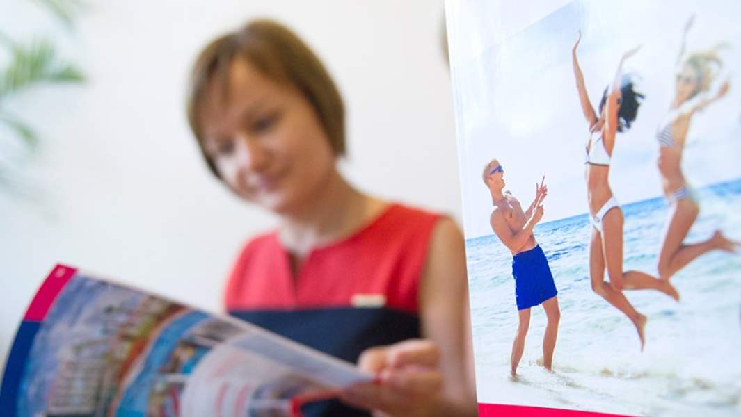 Женщина листает каталог с предложениями туроператора