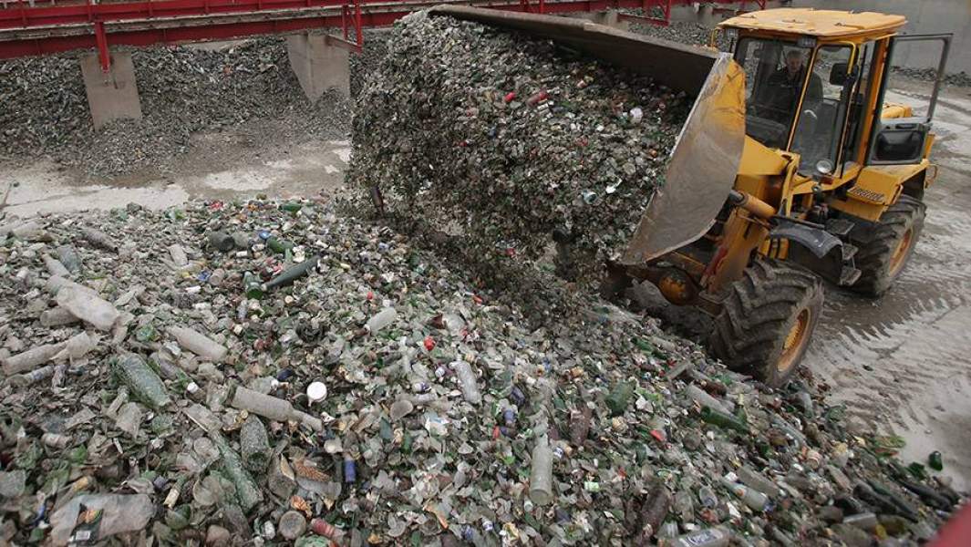 Рабочий грузит стекло на предприятии по сортировке и переработке смешанного тарного стеклобоя