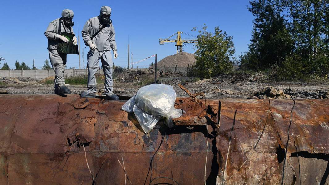 Военнослужащие войск РХБЗ РФ берут пробу вещества из емкости с токсичными отходами на территории заброшенного предприятия