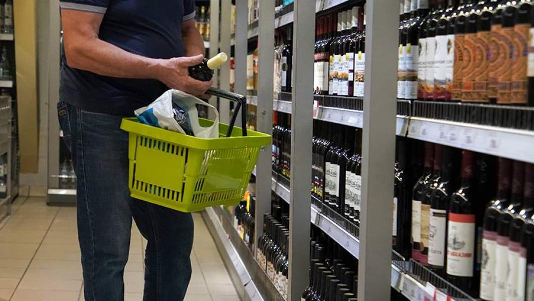 Мужчина выбирает вино в магазине