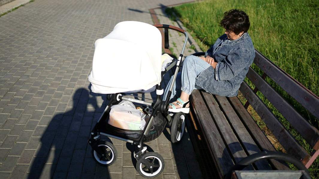 Женщина с коляской на лавочке