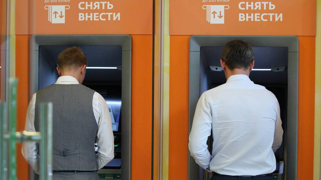 Клиенты снимают деньги в банкоматах