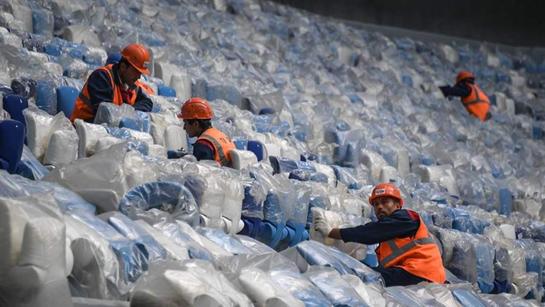 Рабочие монтируют кресла на футбольном стадионе