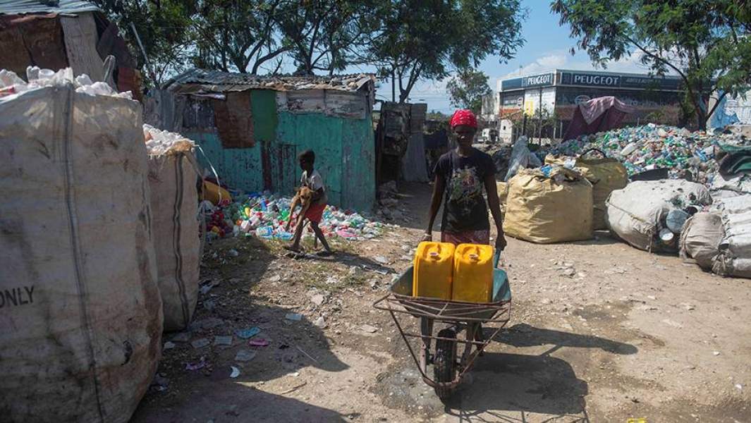 Женщина с канистрами воды в лагере в Порт-о-Пренс
