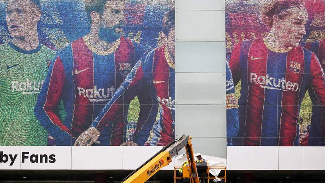 Рабочий убирает баннер с изображением Лионеля Месси со стены стадиона Камп Ноу в Барселоне