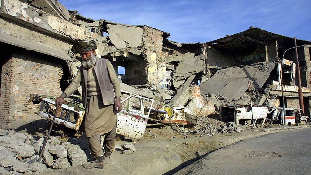 Житель Афганистана на фоне разрушенных домов
