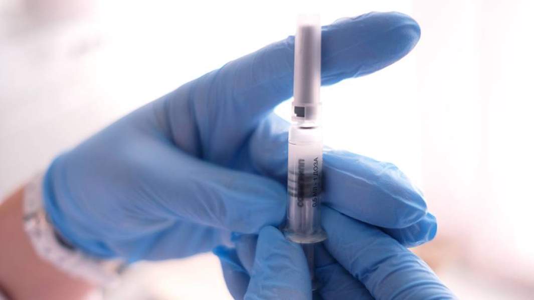Медик готовит шприц с вакциной против гриппа