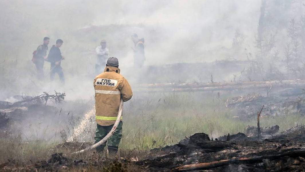 Сотрудник государственной противопожарной службы во время тушения лесного пожара недалеко от села Магарас в Горном улусе в Якутии