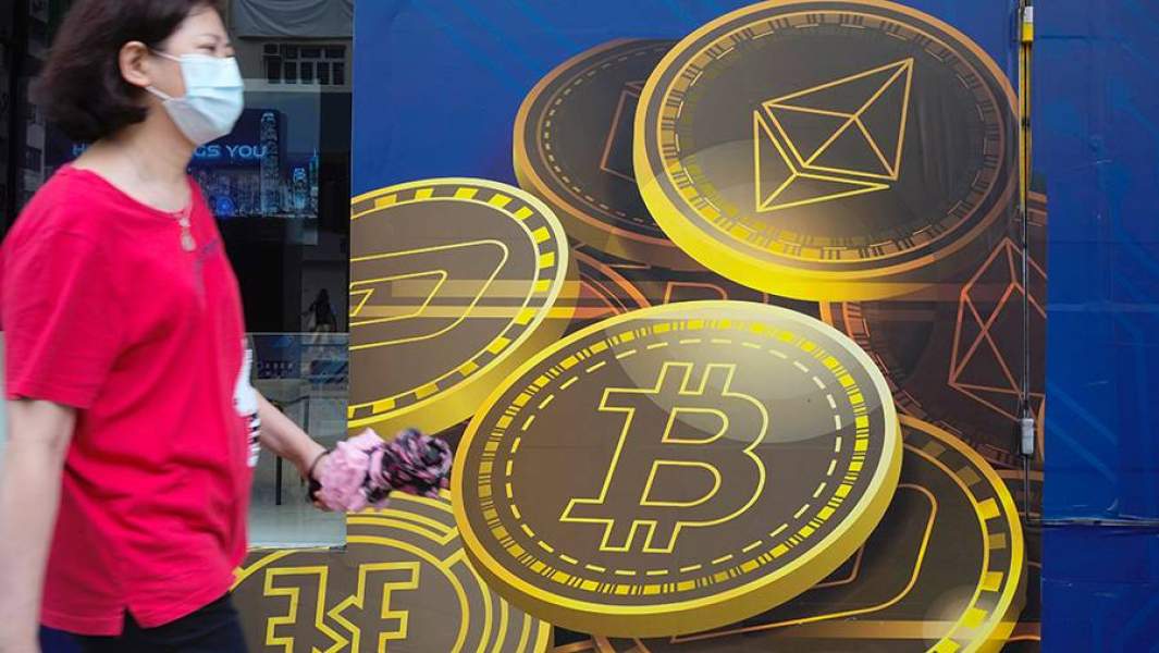 Женщина проходит мимо билборда с изображением криптовалют