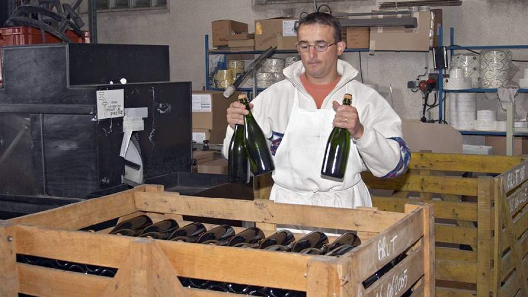 Мужчина складывает бутылки шампанского в ящик