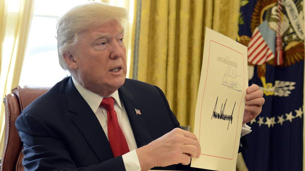 Дональд Трамп демонстрирует свою подпись после подписания законопроекта о снижении налогов 