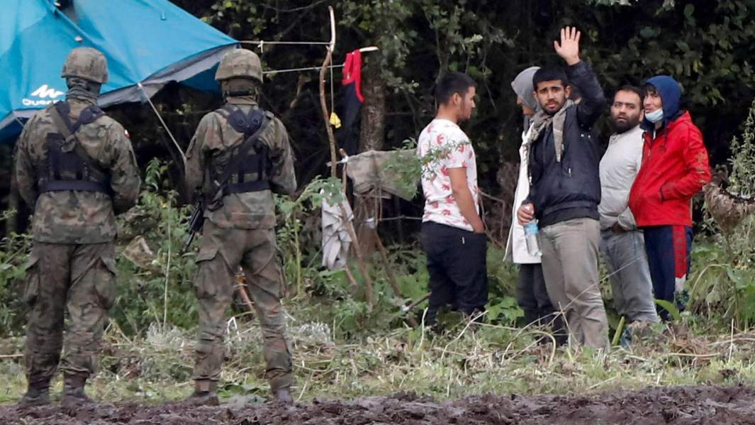 Польские пограничники рядом с группой мигрантов на границе Белоруссии и Польши в районе села Уснарз-Горный, Польша