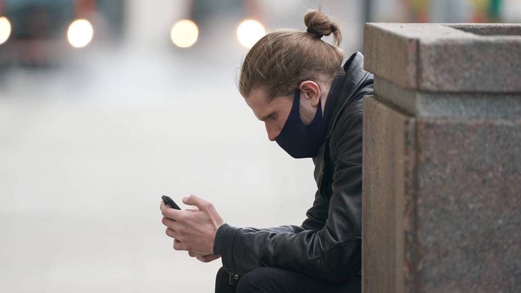 Молодой человек со смартфоном на лавочке