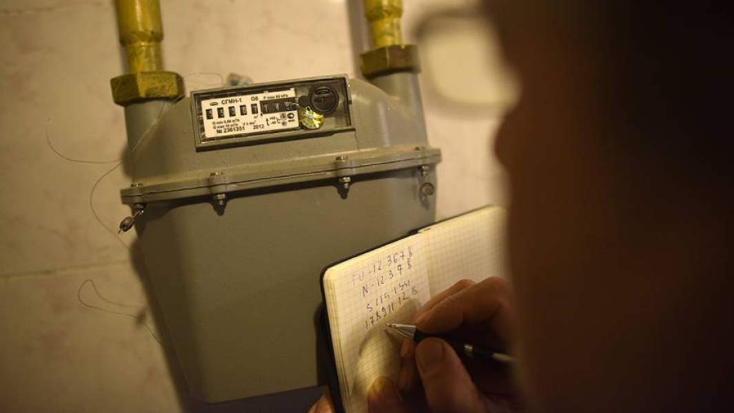 Мужчина снимает показания счетчика на газ