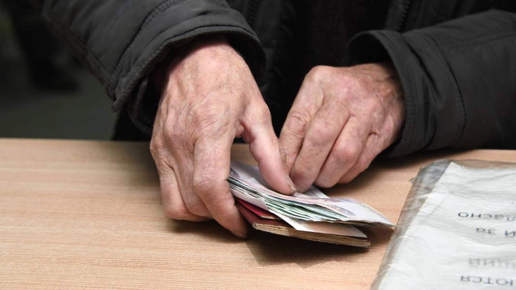 мужчина держит пенсию в руках
