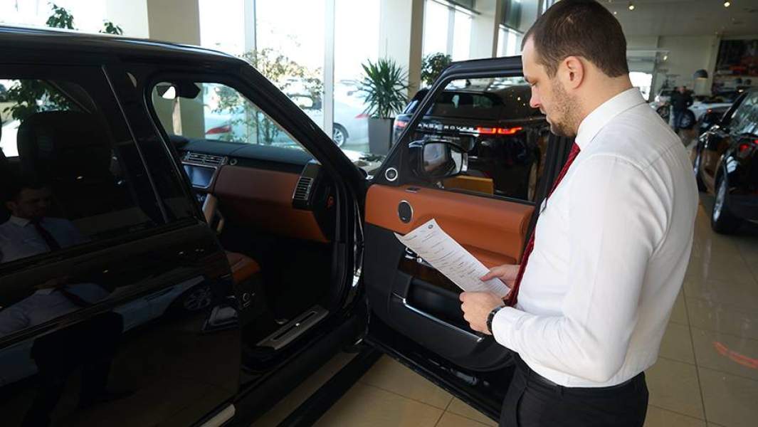 Сотрудник автосалона показывает автомобиль в автосалоне в Краснодарском крае