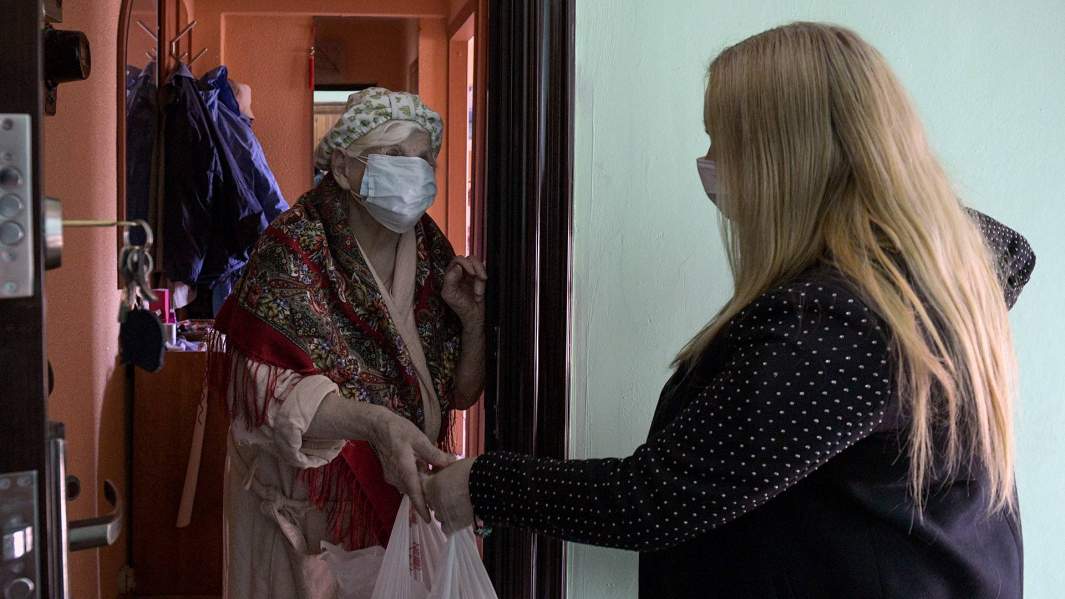 волонтер вручает продуктовый набор пенсионерке