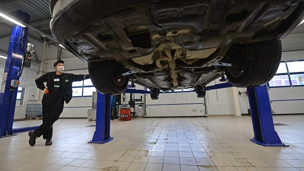 Сотрудник сети центров по обслуживанию автомобилей проводит экспресс-диагностику автомобиля