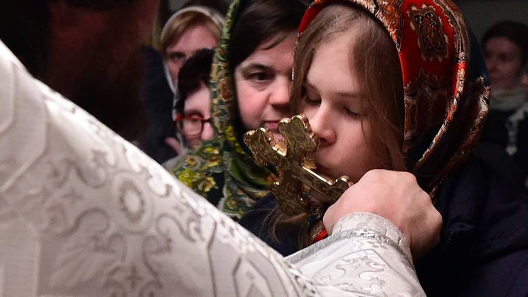 Девушка целует крест в церкви
