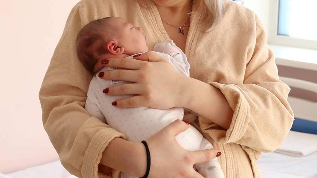 Женщина с новорожденным ребенком в роддоме