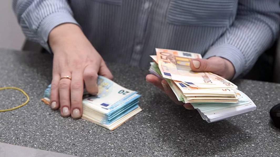 Женщина пересчитывает валюту в банке