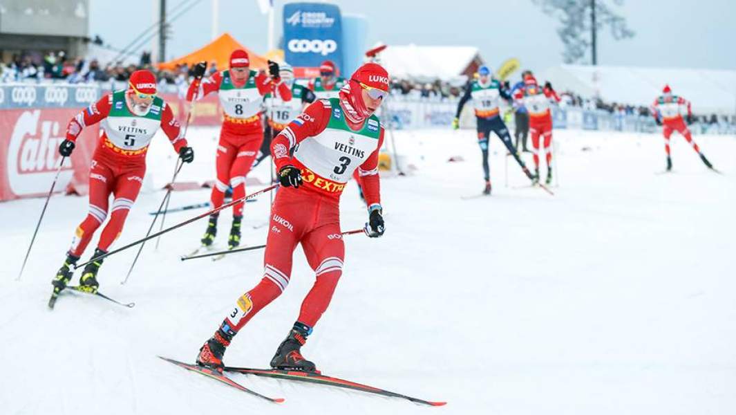 Российский лыжник Александр Большунов (в центре), ставший победителем гонки преследования на дистанции 15 км свободным стилем на первом этапе Кубка мира по лыжным гонкам в Финляндии