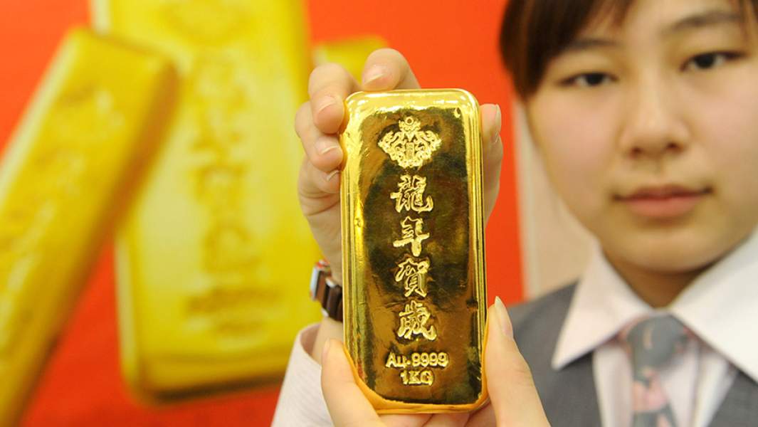 Девушка показывает золотой слиток, сделанный в Китае