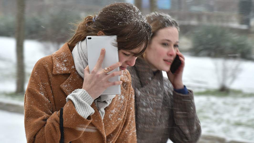 Девушки со смартфонами на улице города